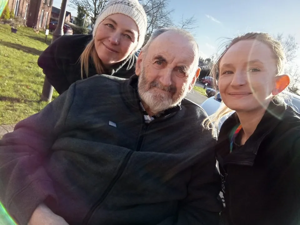 Two Astar Homecare carers smiling with an elderly male client outdoors in the sunshine.