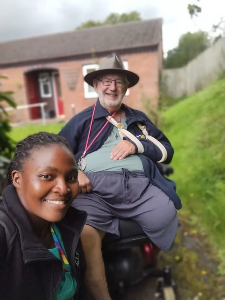 Astar Homecare carer taking a selfie with a happy male client on a mobility scooter outside.