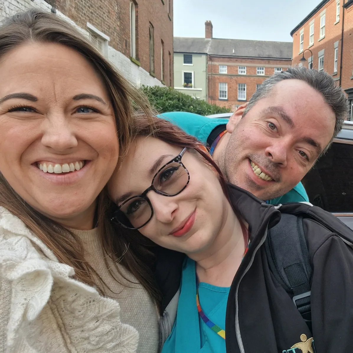 Three smiling Astar Homecare team members taking a cheerful selfie on a street in Whitchurch town centre.