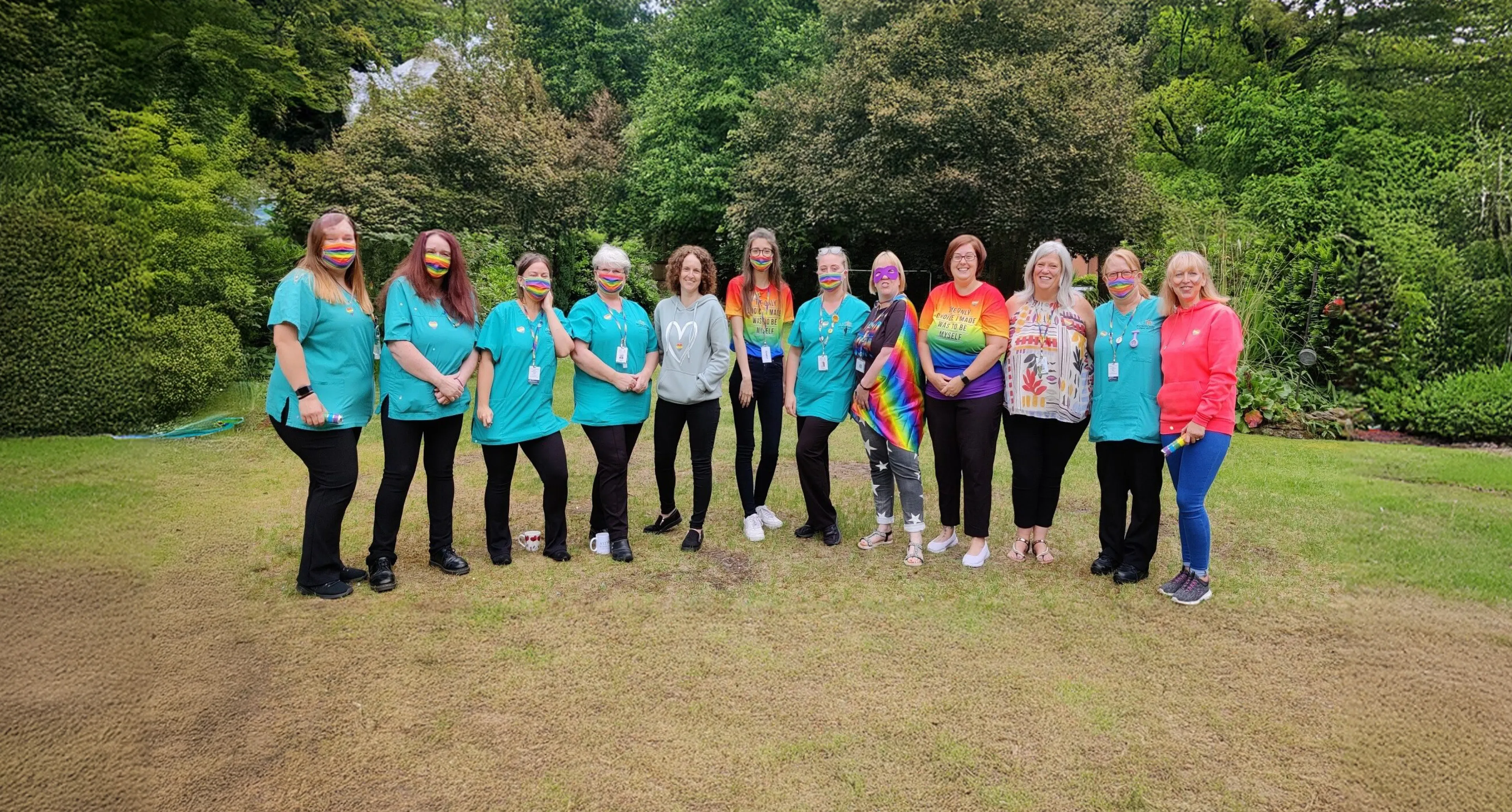 A group of Astar Homecare team members standing together outdoors, wearing colourful and inclusive clothing during a team celebration.